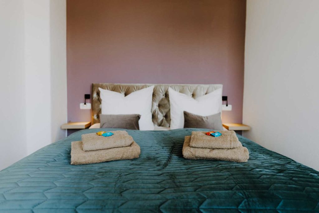 Hotelbett mit Handtüchern und Schokolade